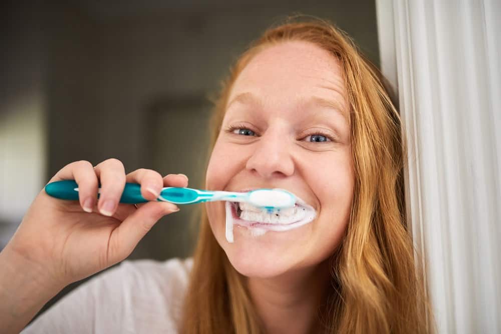 Woman brushing her teeth so her kiss doesn't smell bad